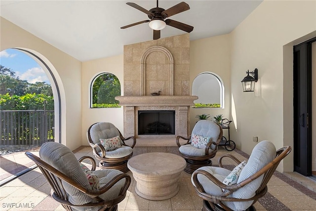 sitting room with vaulted ceiling, ceiling fan, and a tiled fireplace