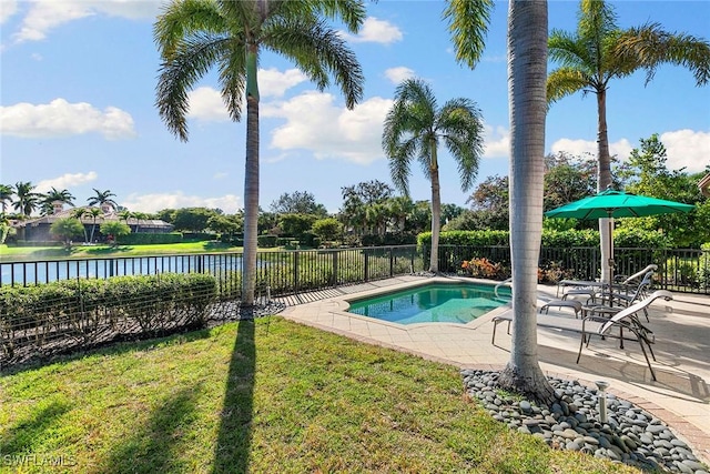 view of pool featuring a patio, a lawn, a water view, and a fenced backyard