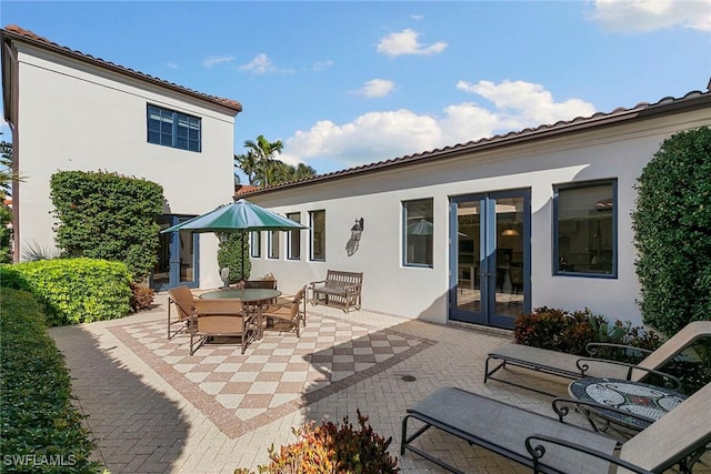 rear view of property featuring a patio, french doors, outdoor dining area, and stucco siding