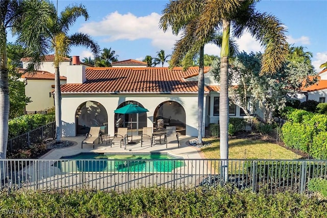 rear view of property featuring a fenced in pool, a patio, stucco siding, fence, and a tiled roof