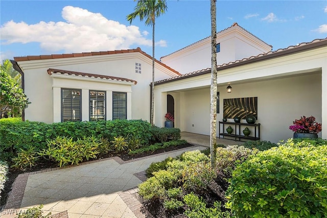 exterior space with a tile roof and stucco siding