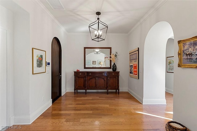 hall with arched walkways, visible vents, crown molding, and light wood finished floors