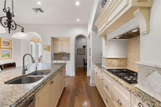 kitchen featuring arched walkways, stainless steel appliances, hanging light fixtures, and a sink