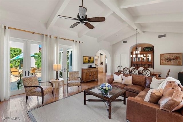 living area featuring high vaulted ceiling, arched walkways, visible vents, and light wood-style flooring