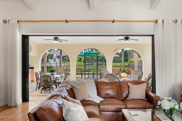 living area featuring light wood-style floors, beam ceiling, a healthy amount of sunlight, and ceiling fan