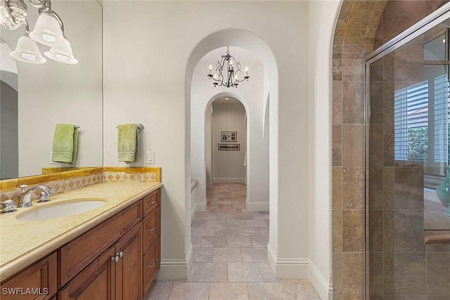 bathroom featuring stone finish flooring, a tile shower, vanity, and baseboards