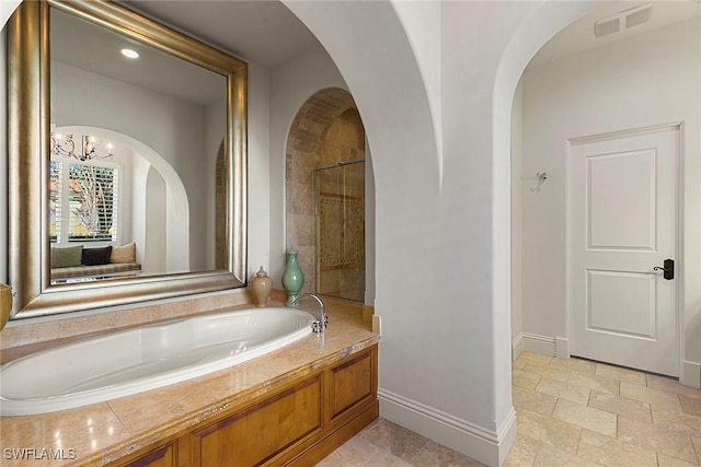 bathroom with a garden tub, stone tile floors, visible vents, baseboards, and tiled shower