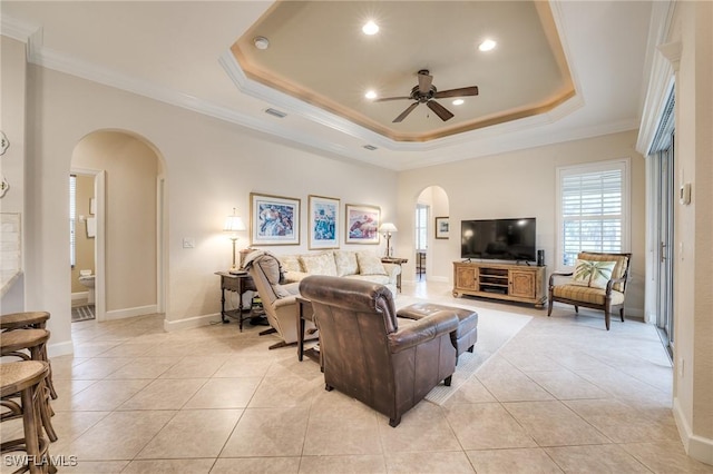 living room featuring ornamental molding, a tray ceiling, and light tile patterned floors