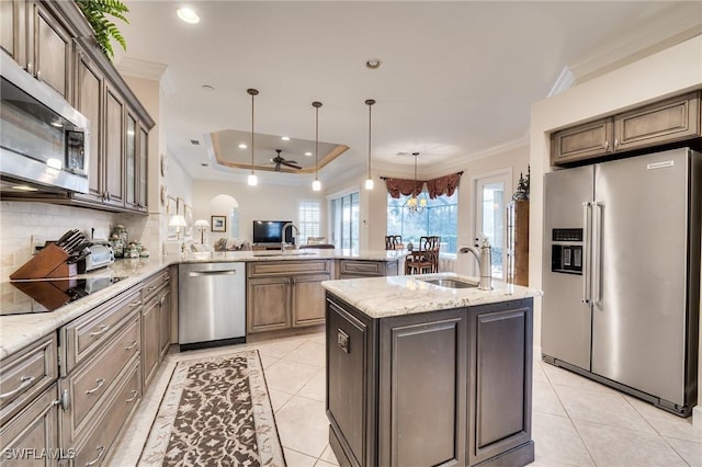 kitchen with sink, hanging light fixtures, a center island with sink, appliances with stainless steel finishes, and kitchen peninsula