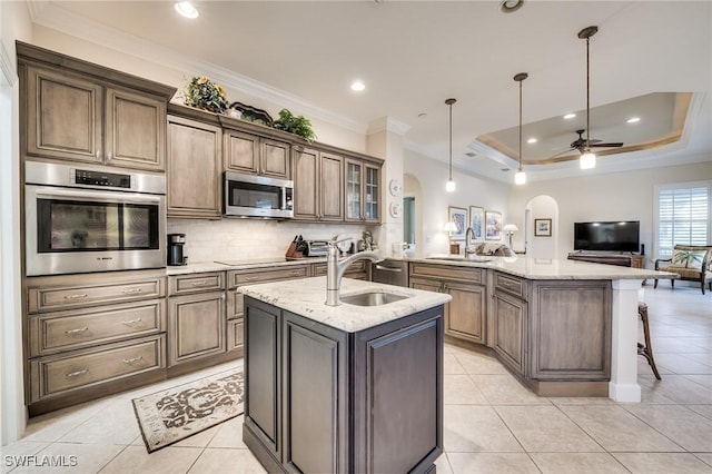 kitchen featuring decorative light fixtures, sink, light stone counters, kitchen peninsula, and stainless steel appliances