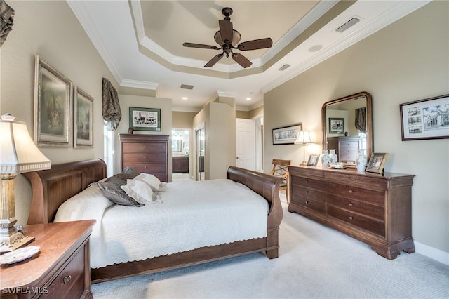 bedroom with crown molding, connected bathroom, a tray ceiling, and light colored carpet