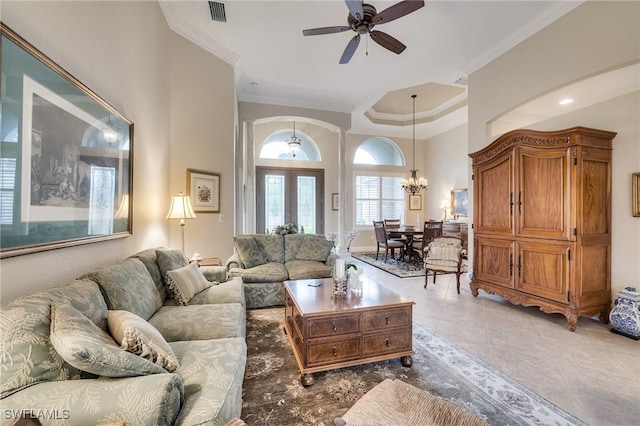 tiled living room with ceiling fan with notable chandelier and ornamental molding