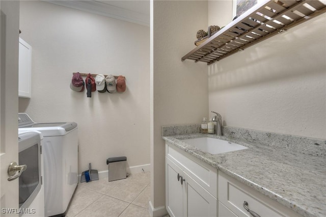 laundry room featuring light tile patterned flooring, washer and dryer, sink, cabinets, and ornamental molding