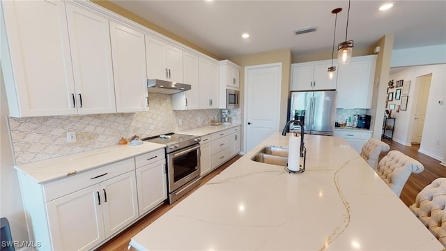 kitchen with hanging light fixtures, sink, white cabinets, and appliances with stainless steel finishes