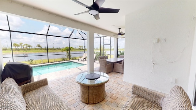 view of pool with area for grilling, ceiling fan, glass enclosure, a water view, and a patio area