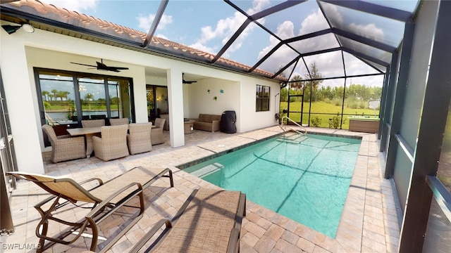 view of swimming pool featuring ceiling fan, an outdoor hangout area, a patio area, and glass enclosure