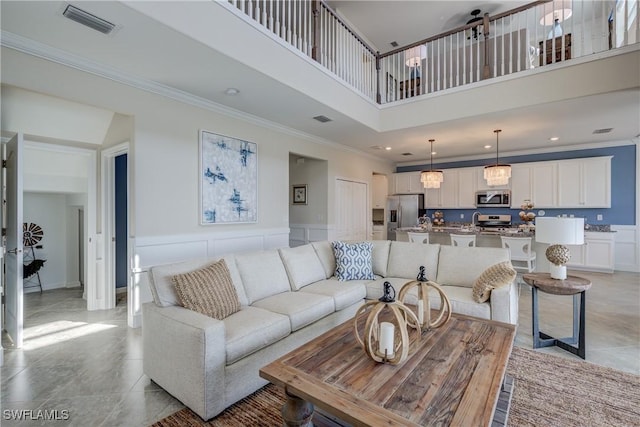 living room featuring sink, a high ceiling, crown molding, and light tile patterned floors