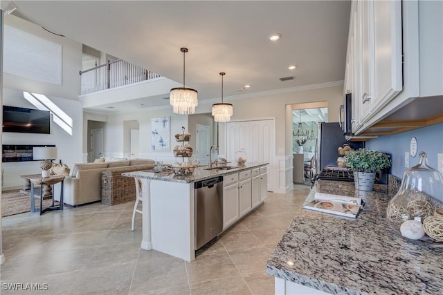 kitchen with hanging light fixtures, appliances with stainless steel finishes, sink, white cabinetry, and a kitchen island with sink