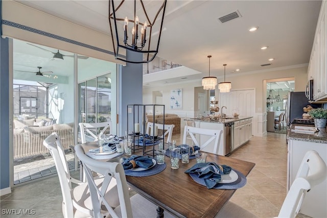 dining space featuring ceiling fan with notable chandelier, sink, crown molding, and light tile patterned flooring