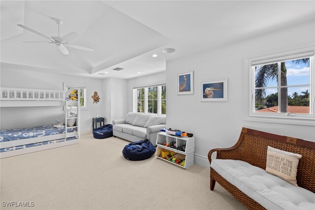 bedroom featuring ceiling fan, a tray ceiling, and carpet