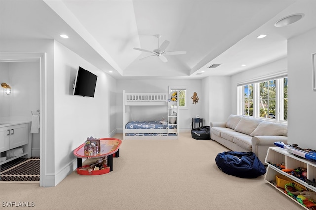 carpeted bedroom featuring ceiling fan and a raised ceiling