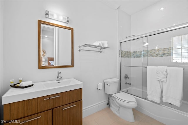 bathroom with baseboards, toilet, shower / bath combination with glass door, tile patterned flooring, and vanity