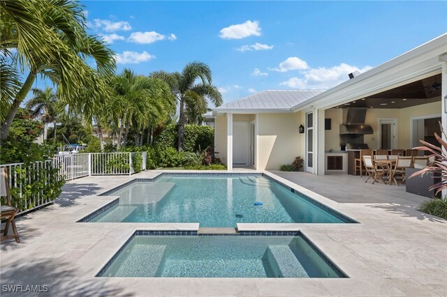 view of swimming pool with a patio area, exterior kitchen, an outdoor bar, and an in ground hot tub