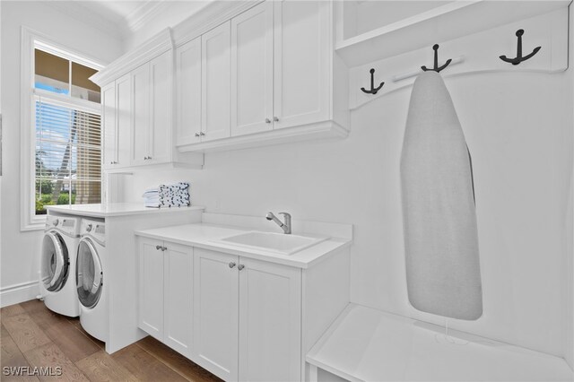 washroom featuring sink, crown molding, cabinets, wood-type flooring, and washer and dryer