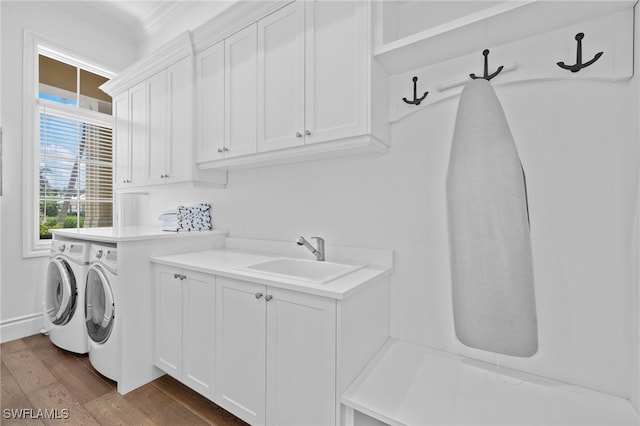 washroom with crown molding, cabinet space, dark wood-type flooring, a sink, and separate washer and dryer