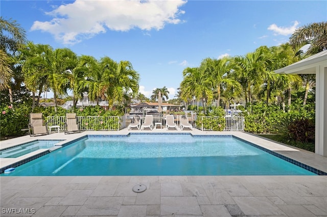 view of swimming pool featuring a patio area, fence, and a pool with connected hot tub