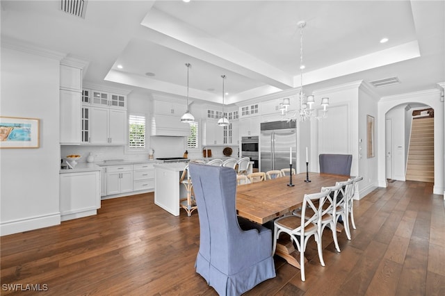 dining area featuring visible vents, a tray ceiling, arched walkways, and dark wood-type flooring