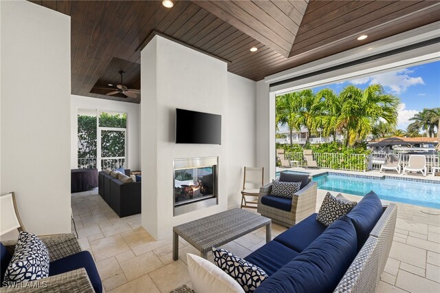 view of patio / terrace with ceiling fan, a fenced in pool, and an outdoor living space with a fireplace