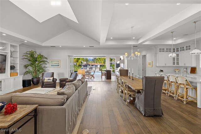 living room featuring a chandelier, recessed lighting, built in features, wood-type flooring, and a raised ceiling