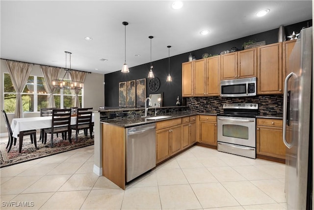 kitchen featuring appliances with stainless steel finishes, dark stone countertops, sink, hanging light fixtures, and light tile patterned floors