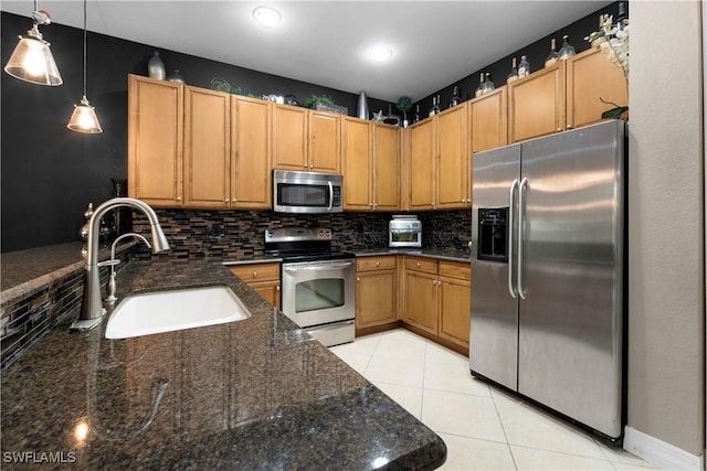 kitchen with appliances with stainless steel finishes, decorative light fixtures, dark stone countertops, tasteful backsplash, and sink