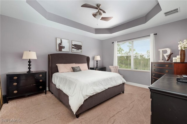 carpeted bedroom with ceiling fan and a raised ceiling