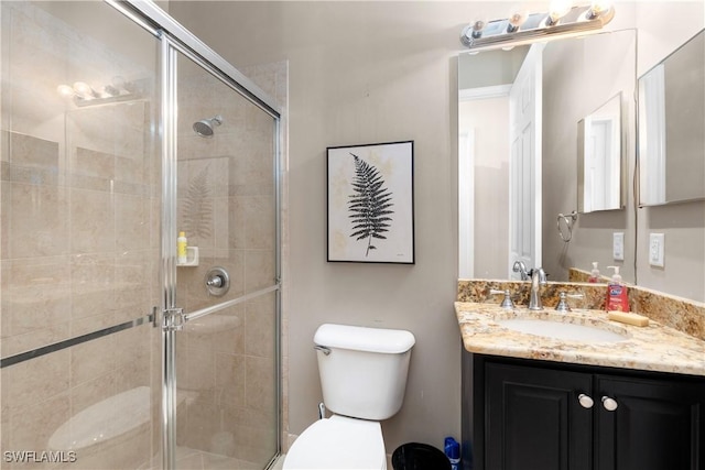 bathroom with vanity, toilet, and a shower with shower door