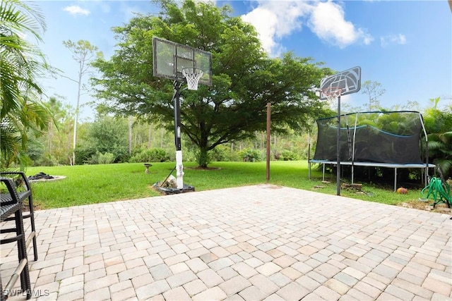 view of basketball court featuring a yard and a trampoline