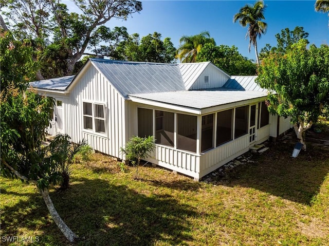 back of house featuring a lawn and a sunroom