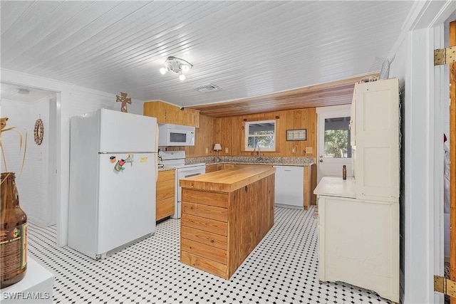 kitchen featuring sink, butcher block countertops, a center island, wooden walls, and white appliances