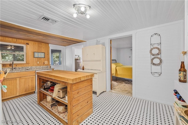 kitchen featuring sink, light brown cabinets, and wood walls