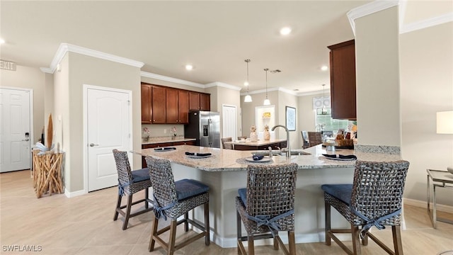 kitchen featuring light stone countertops, sink, a kitchen breakfast bar, stainless steel fridge with ice dispenser, and kitchen peninsula