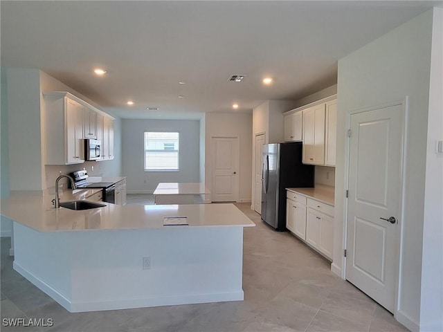 kitchen with white cabinets, kitchen peninsula, appliances with stainless steel finishes, and sink