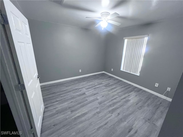 spare room with baseboards, ceiling fan, and wood finished floors