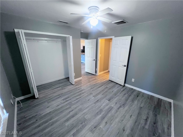 unfurnished bedroom featuring baseboards, visible vents, wood finished floors, and a closet