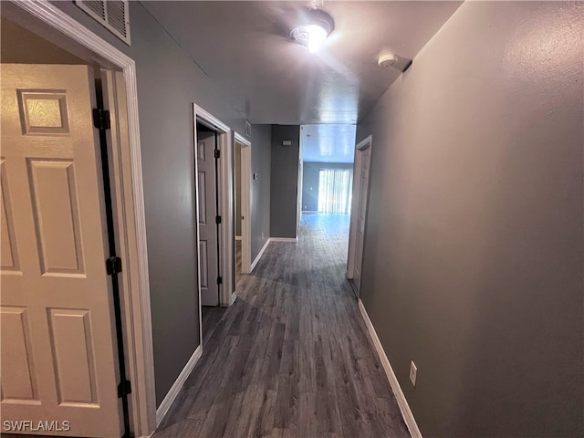corridor with baseboards, dark wood-style floors, and visible vents