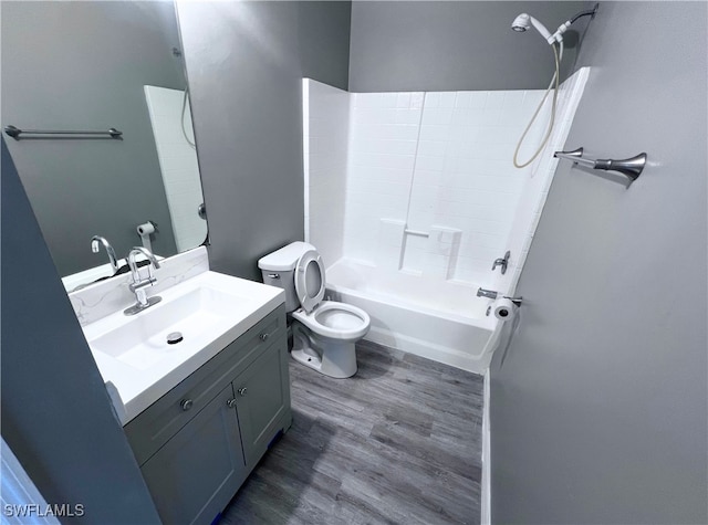 bathroom with vanity, wood finished floors, toilet, and shower / washtub combination