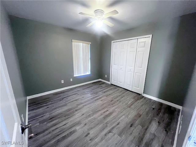 unfurnished bedroom featuring baseboards, ceiling fan, a closet, and wood finished floors