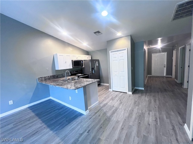 kitchen with a peninsula, appliances with stainless steel finishes, dark stone countertops, and visible vents