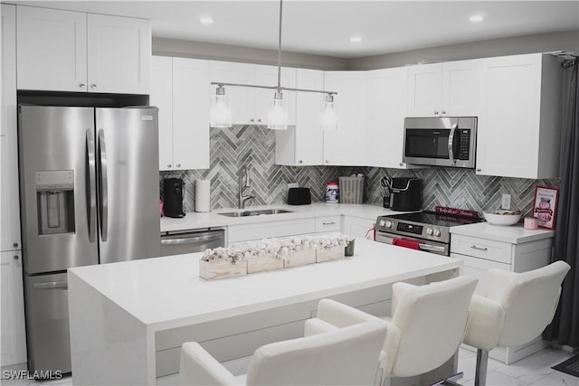 kitchen featuring appliances with stainless steel finishes, sink, a breakfast bar area, hanging light fixtures, and a center island